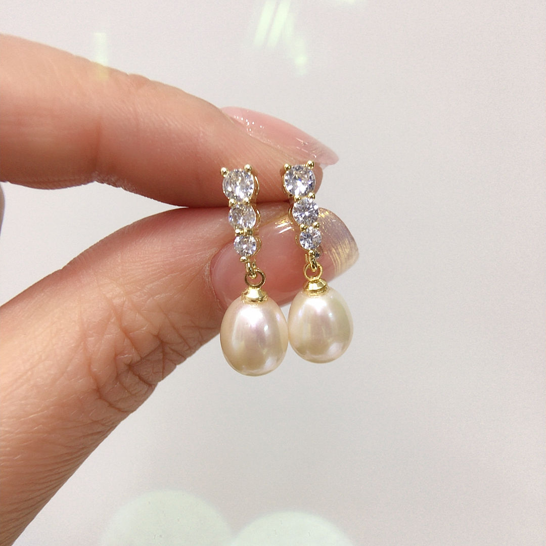 Boucles d'oreilles perles et strass entre les doigts