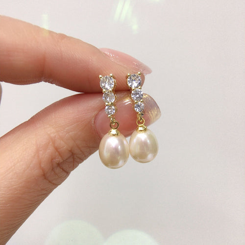 Boucles d'oreilles perles et strass entre les doigts